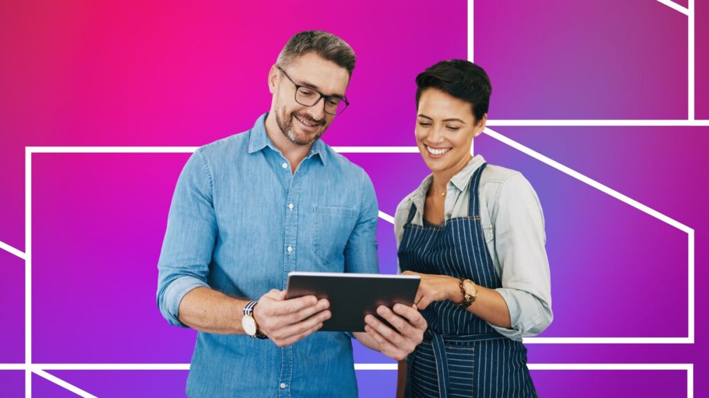 Two people smiling while looking at a tablet together. One person wears a light blue button-up shirt and glasses, and the other wears a striped apron over a light shirt. The background is a bright pink-to-purple gradient with white geometric line patterns.