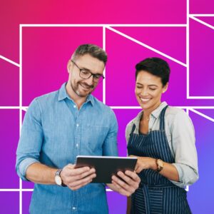 Two people smiling while looking at a tablet together. One person wears a light blue button-up shirt and glasses, and the other wears a striped apron over a light shirt. The background is a bright pink-to-purple gradient with white geometric line patterns.