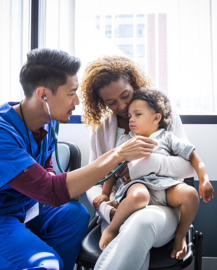 Male nurse examining baby girl with stethoscope in hospital