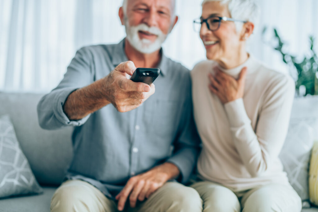 A couple sitting on a couch looking at the television.