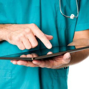 Someone in medical scrubs holding a tablet and typing on it.