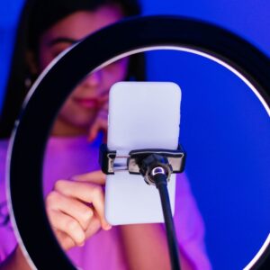 A young women using a phone that's attached to a ring light