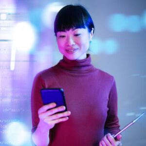 Woman standing with a cell phone, with coding imagery overlaying the left side of the image.