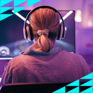 A woman sitting at a computer gaming. She has headphones on.