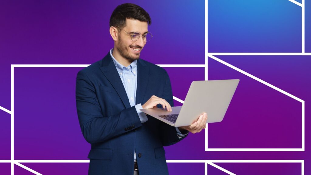 A man holding a laptop in front of a purple and blue geometric background