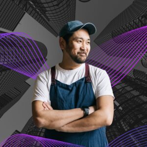 A man in a blue apron standing in front of a building background and purple swirls