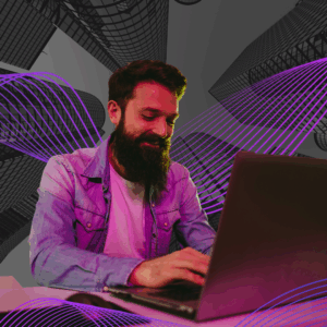 A man with a beard and denim jacket smiles while typing on a laptop. The background features abstract wireframe skyscrapers and flowing purple lines on a dark backdrop, creating a futuristic and creative atmosphere.