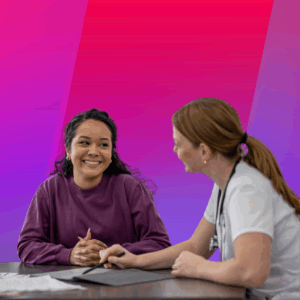 A insurance professional talks with a smiling patient across a table, with papers and a pen in front of them. The background is a gradient of pink and purple tones.