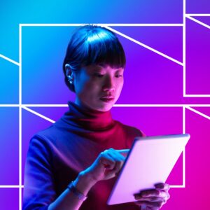 A woman uses a tablet with a focused expression, illuminated by blue and pink lighting against a vibrant blue, pink, and purple background with geometric line patterns, suggesting digital interaction and modern technology use.