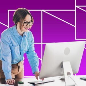 A woman wearing glasses smiles while working at a desktop computer beside an adjustable desk lamp, set against a vibrant purple background with white geometric line accents.