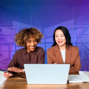 Two professionals smile while reviewing a laptop together at a desk, with a tablet, papers, and notebook nearby, set against a blue and purple office-inspired background.